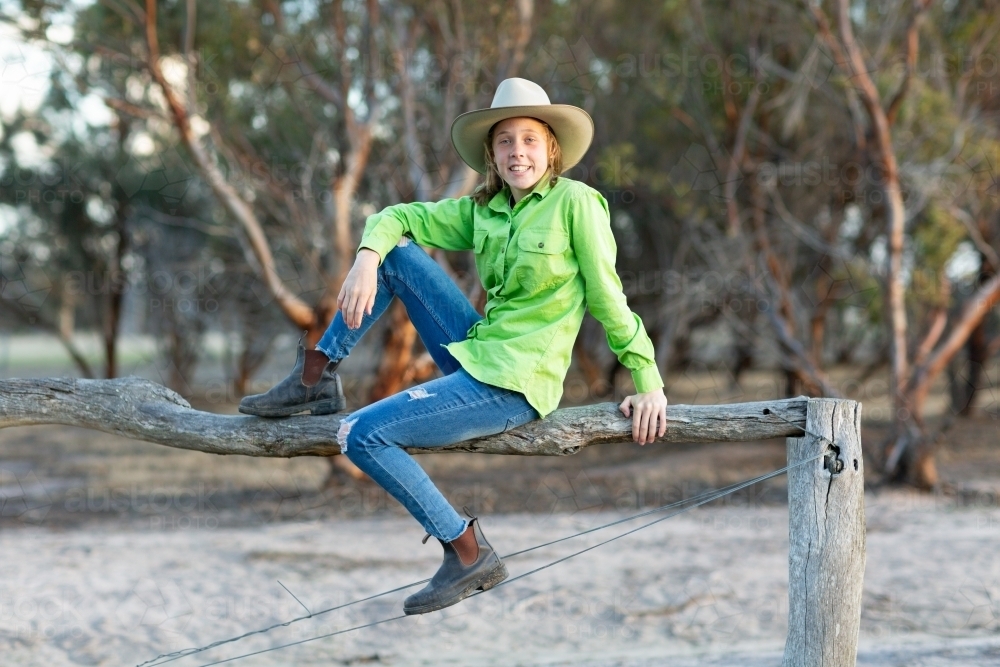 country girl sitting on fence - Australian Stock Image