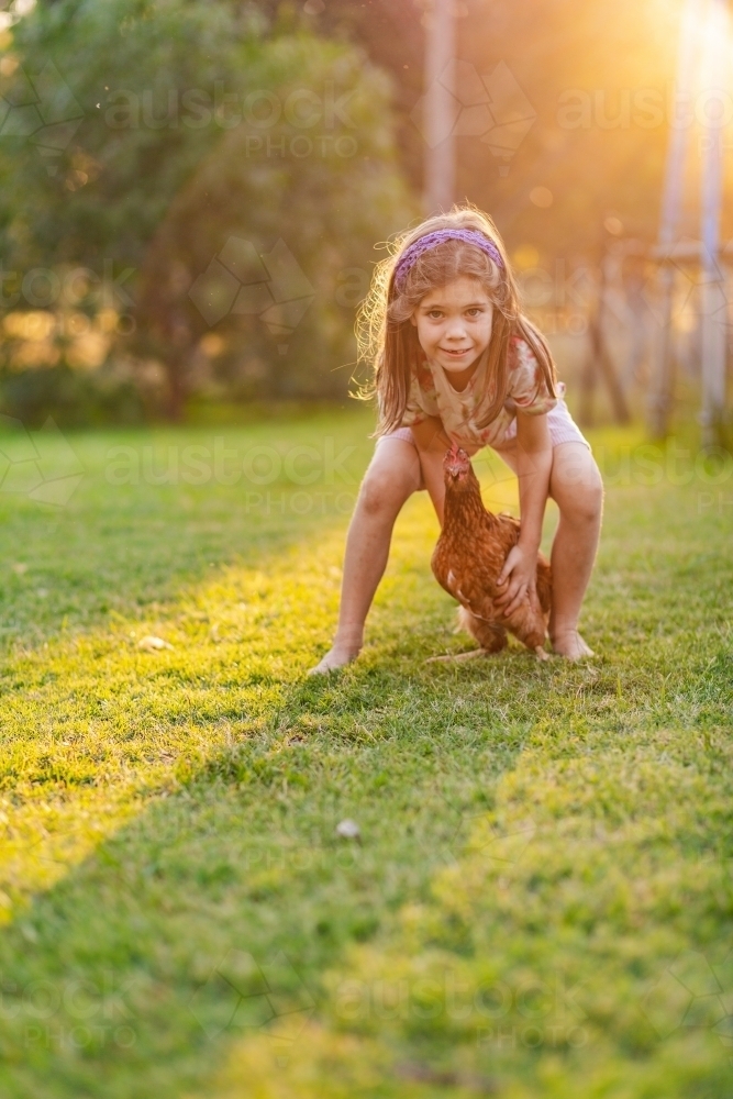 Country kid chasing chook around backyard on farm - Australian Stock Image