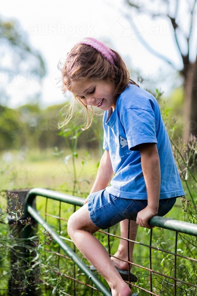 Country kid climbing over farm gate - Australian Stock Image