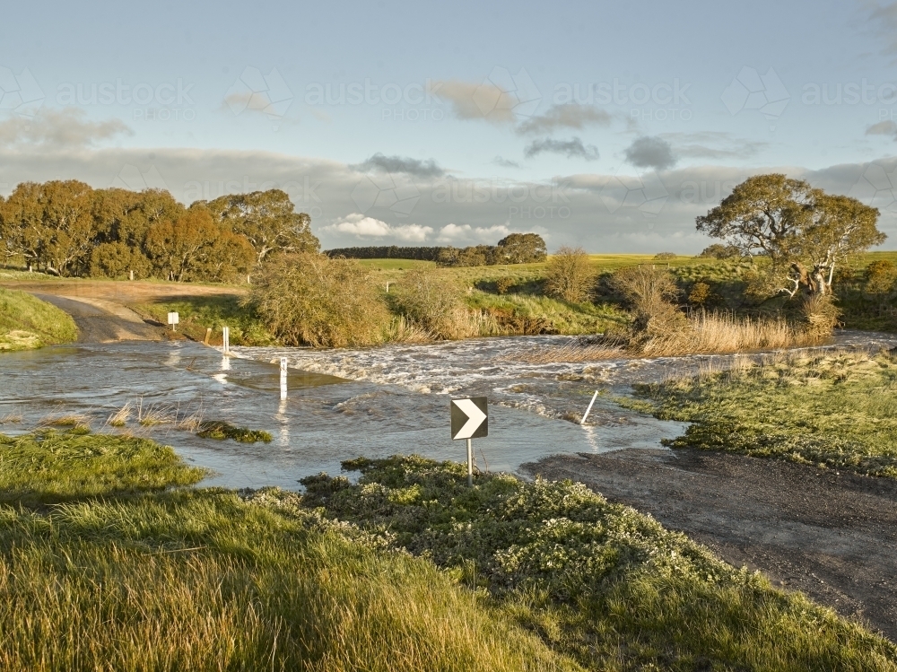 country road leading through flooded causeway - Australian Stock Image