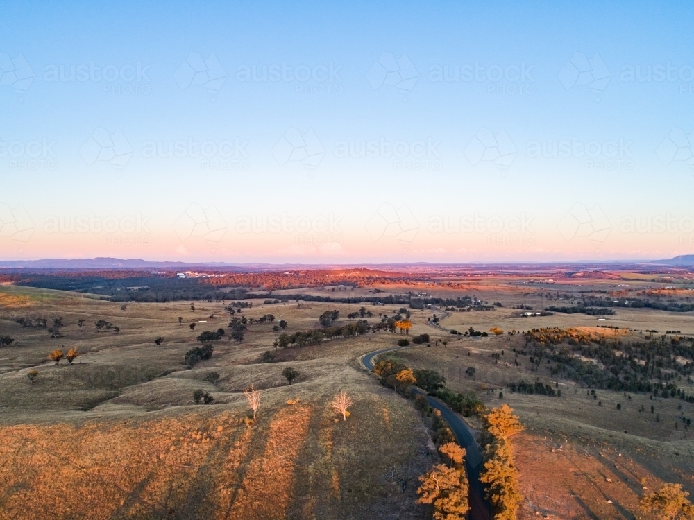 Country road winding away over hills at sunset - Australian Stock Image