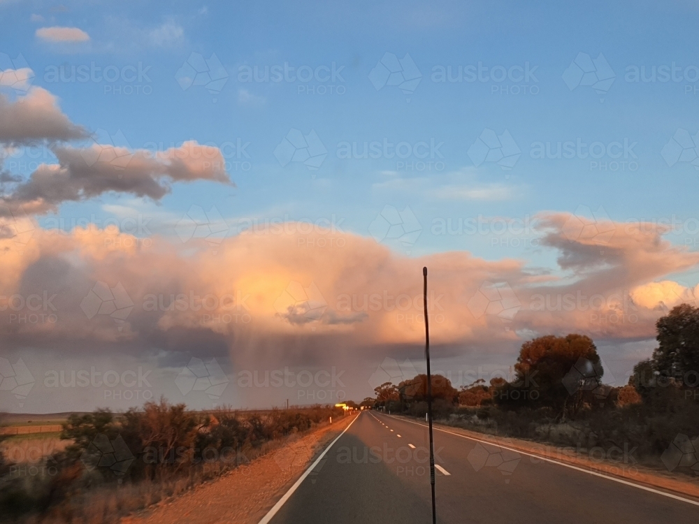 country road with sunlit clouds in distance - Australian Stock Image