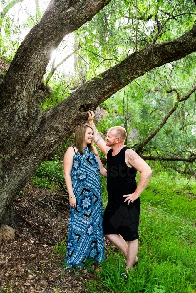 Couple standing together outside under willow tree - Australian Stock Image