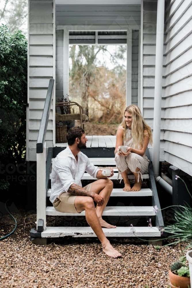 Couple talking on the steps of their front verandah - Australian Stock Image