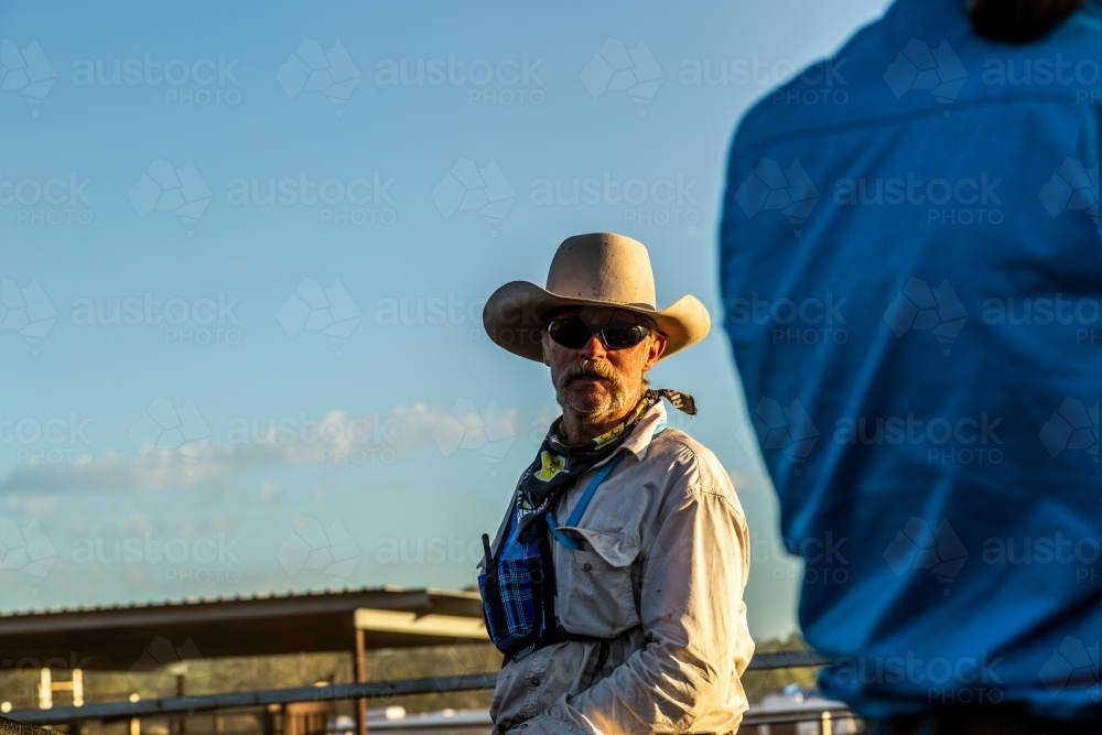 Cowboy facing camera, talking to a cowgirl. - Australian Stock Image