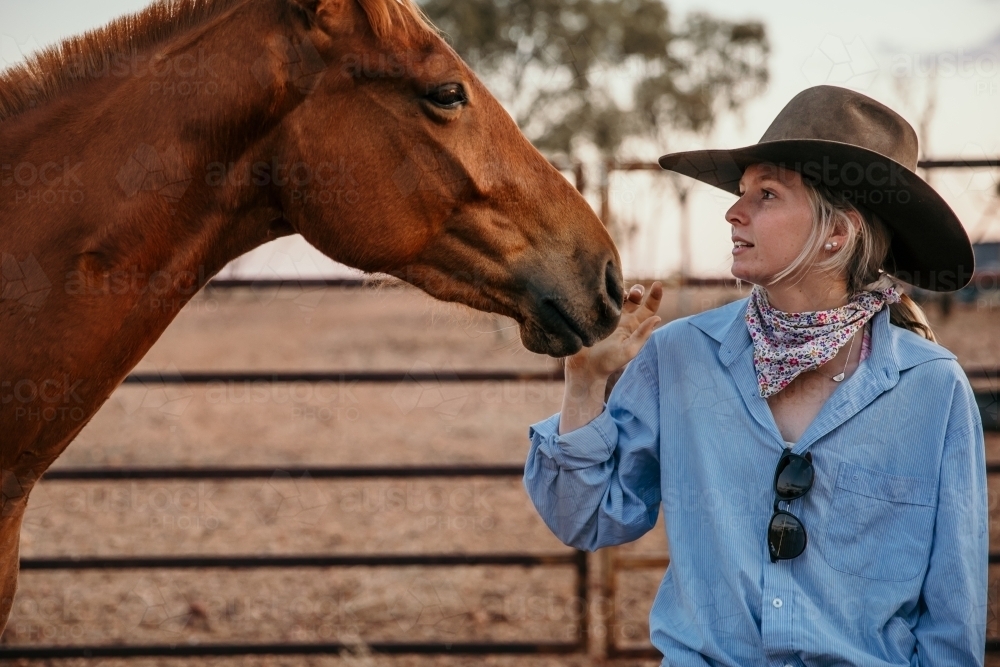 Cowgirl patting horse - Australian Stock Image