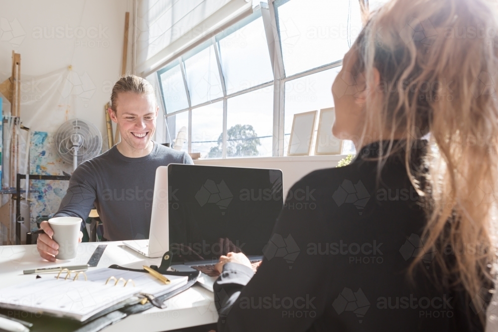 Coworkers at a shared desk in a creative studio workplace - Australian Stock Image