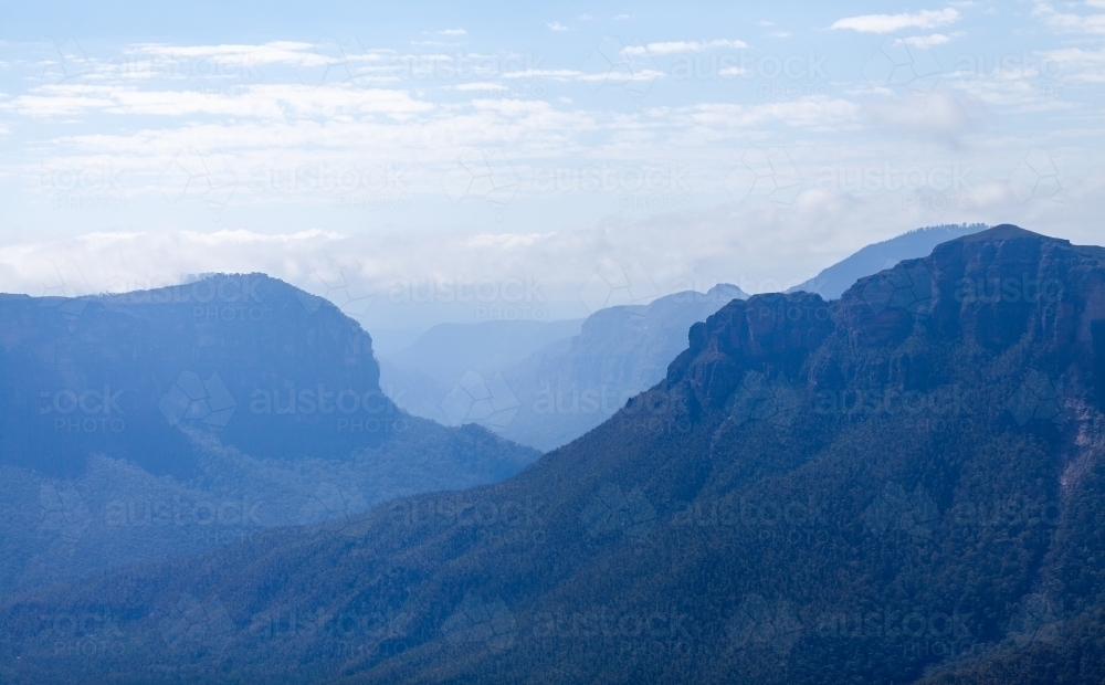 craggy blue mountain ranges fade into distance - Australian Stock Image