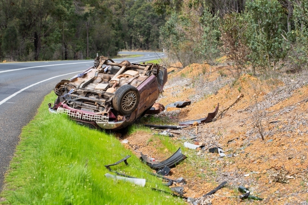 Crashed car upside down on side of country road - Australian Stock Image