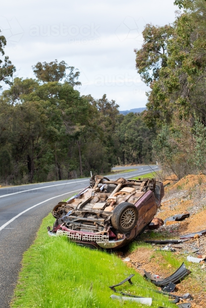 Crashed vehicle upside down on side of highway - Australian Stock Image