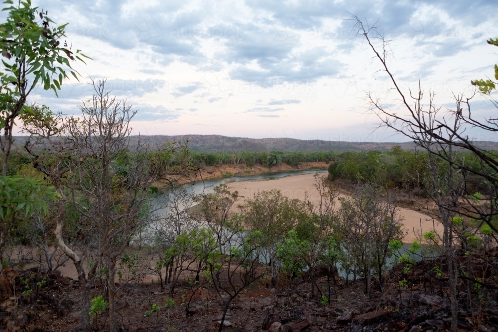 Creek winding around sandy bank surrounded by bushland - Australian Stock Image