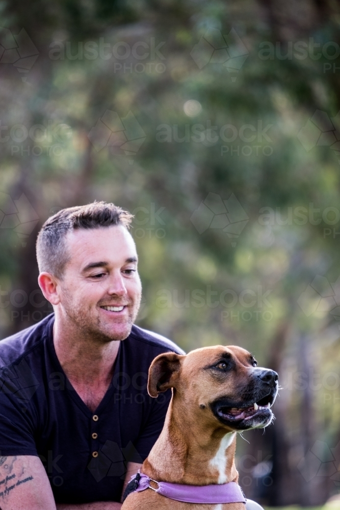 Cross breed large Dog and male owner sitting behind looking at dog - Australian Stock Image