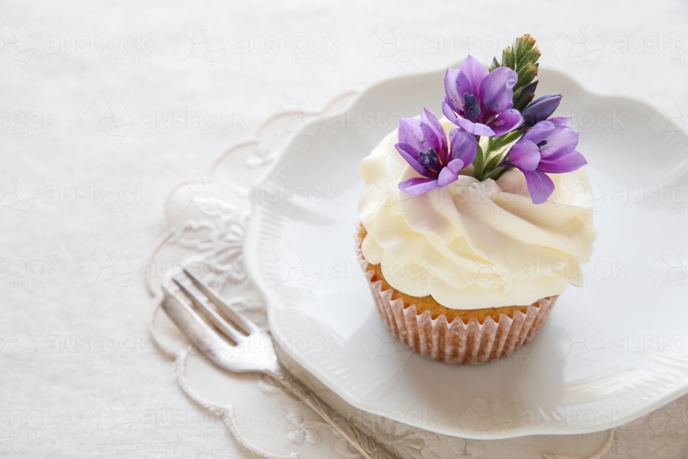 cupcakes with purple edible flowers for tea party - Australian Stock Image