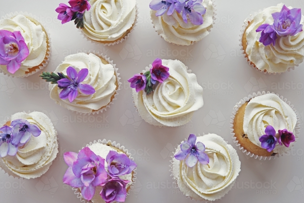 Cupcakes with purple edible flowers for tea party - Australian Stock Image