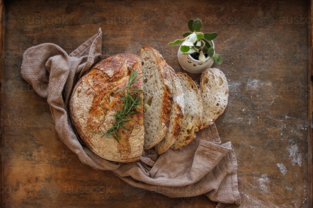 Cut sourdough on wooden tray with brown linen tea towel - Australian Stock Image