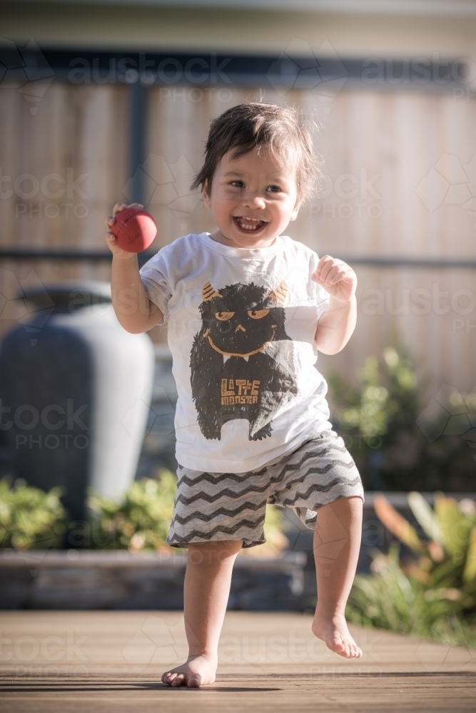 Cute 1 year old boy takes his first steps outside in his suburban backyard - Australian Stock Image