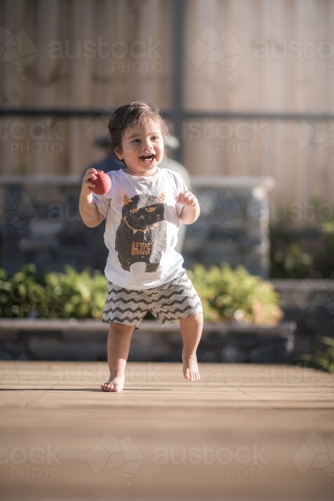 Cute 1 year old boy takes his first steps outside in his suburban backyard - Australian Stock Image