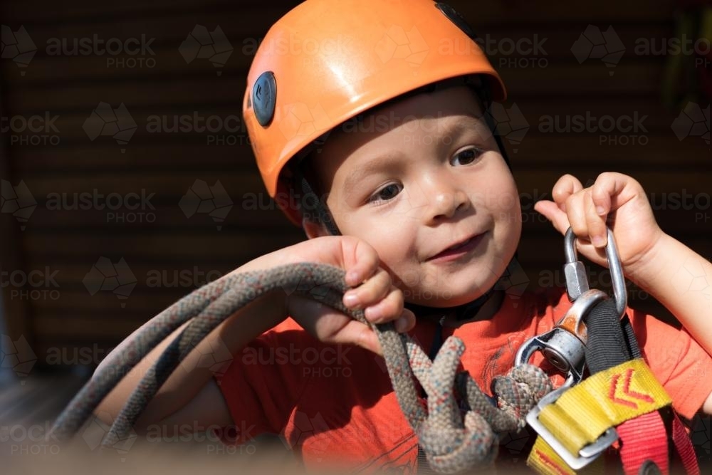 Cute 3 year old mixed race boy prepares to play on an adventure ropes course - Australian Stock Image