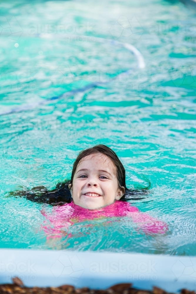 Cute four year old girl swimming in backyard pool - Australian Stock Image