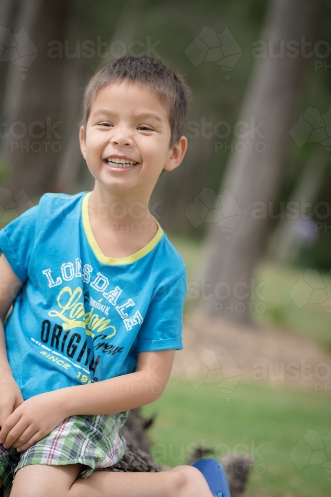 Cute mixed race boy playing in a park outside among the trees - Australian Stock Image