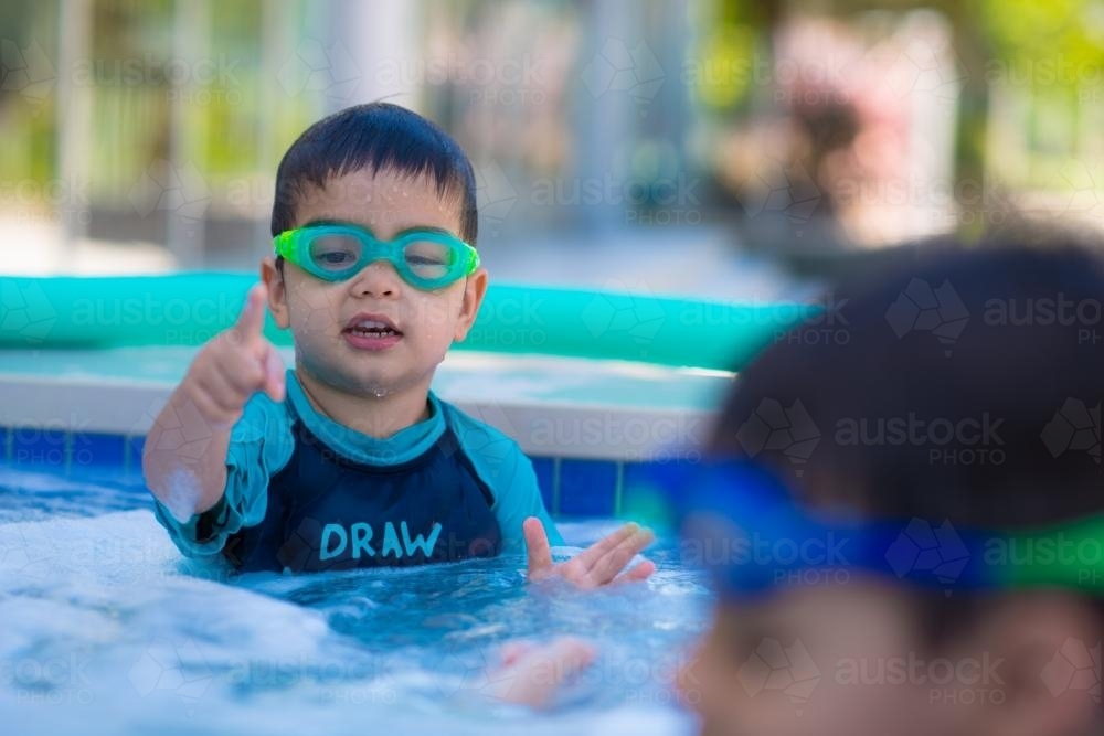 Cute mixed race boys play in the bubbles of a backyard spa - Australian Stock Image