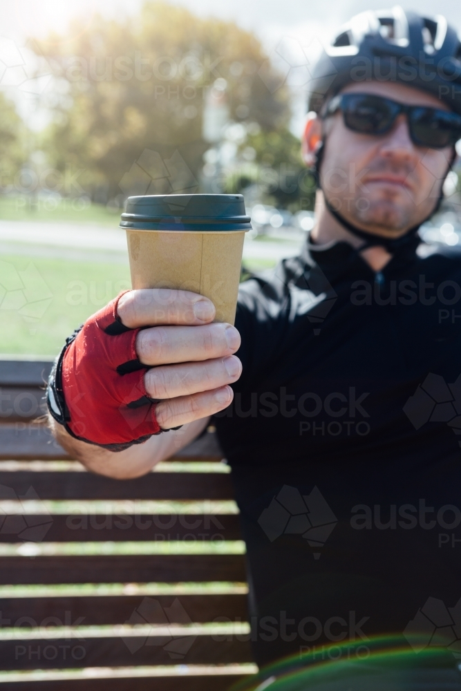 Cyclist taking a break holding a cup of coffee - Australian Stock Image