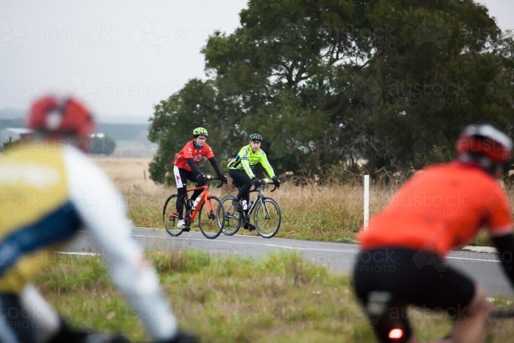 Cyclists waiting at intersection for another group to pass - Australian Stock Image