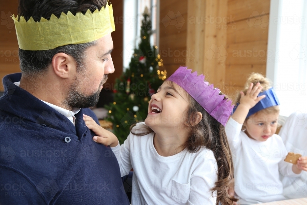 Dad and daughter looking at each other wearing Christmas hats - Australian Stock Image