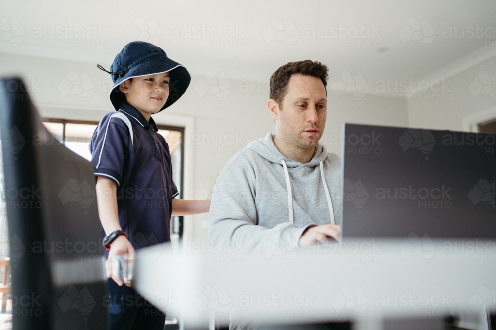 Dad helping kids with their homework using laptop. - Australian Stock Image