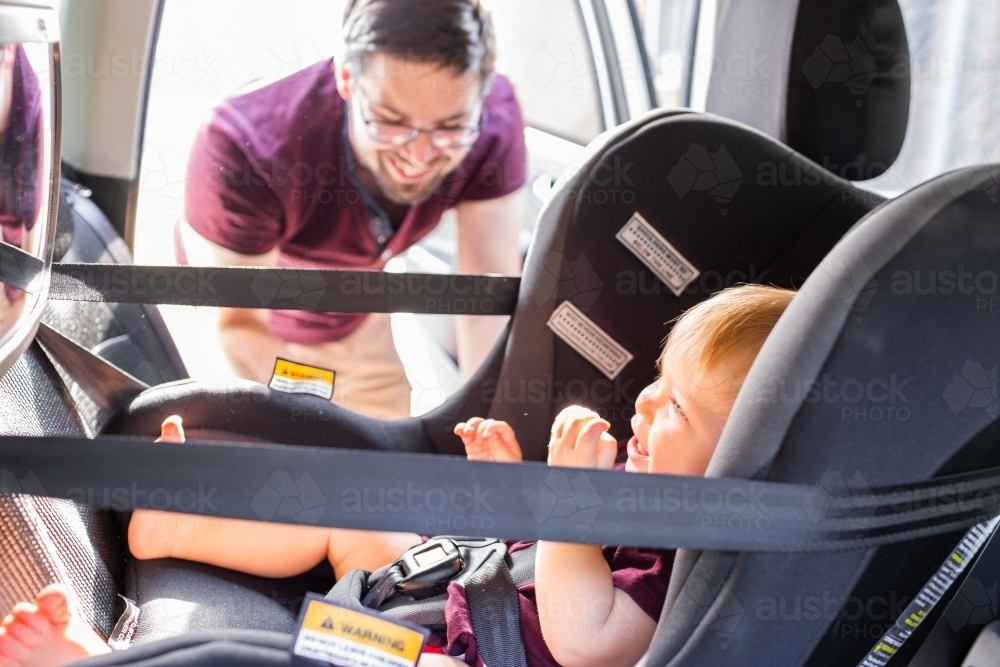 dad in car with one year old child in rear facing car seat - Australian Stock Image