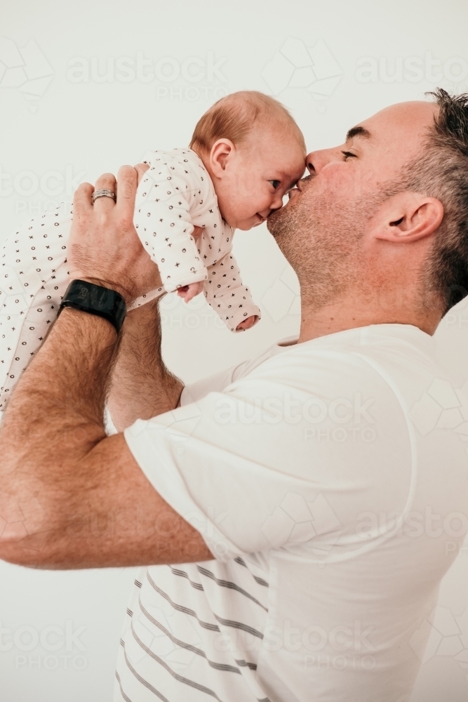 Dad kisses smiling baby girl. - Australian Stock Image