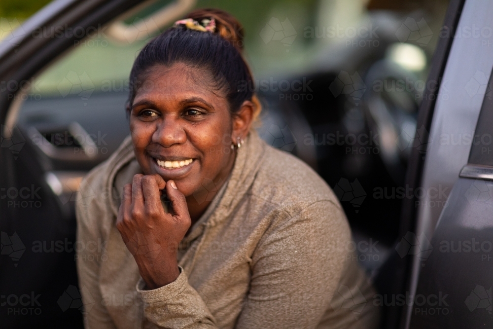 dark-skinned woman looking out of car passenger seat - Australian Stock Image