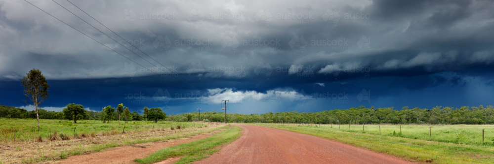 Dark storm cloud over red dirt gravel road in the Northern Territory - Australian Stock Image