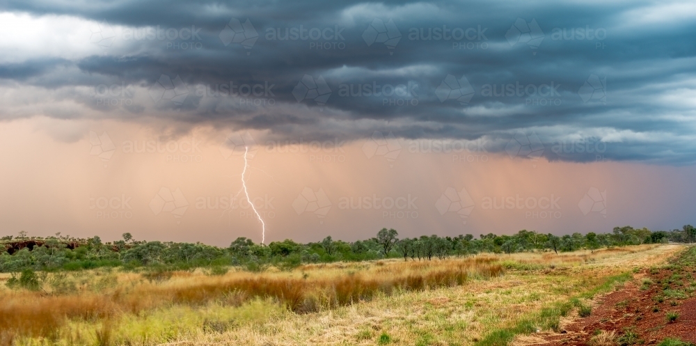 Dark storm clouds with lightning bolt hitting towards the ground. - Australian Stock Image