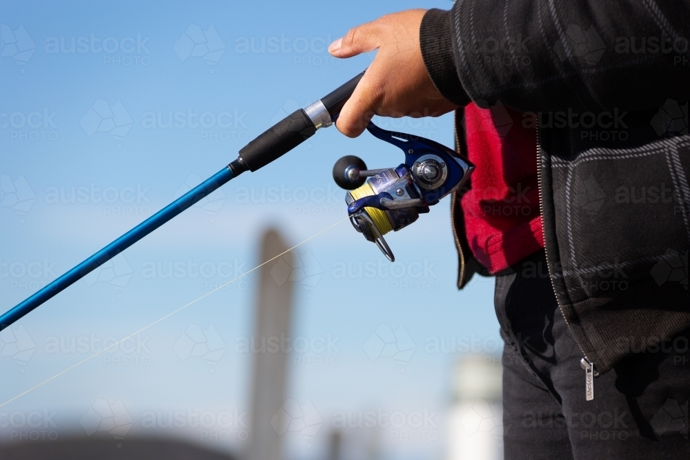 Detail of person fishing with rod and reel - Australian Stock Image