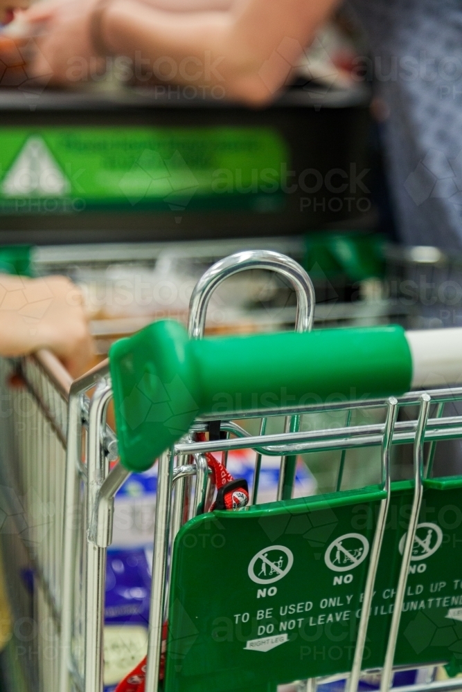 Detail of shopping trolley handle at supermarket checkout counter - Australian Stock Image