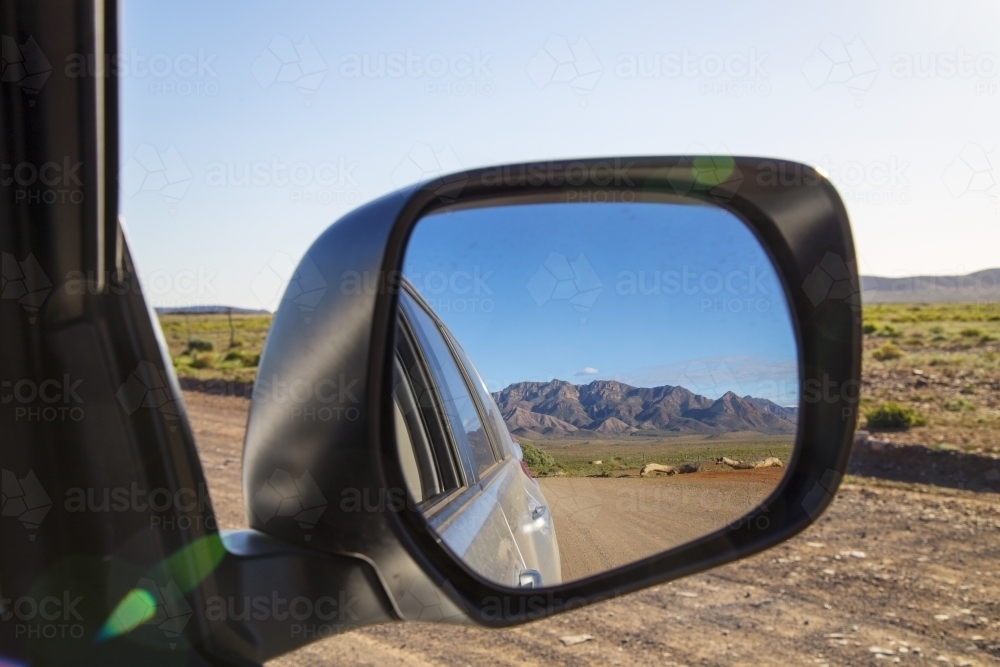 Dirt road and rugged mountains in the side mirror of a 4wd - Australian Stock Image