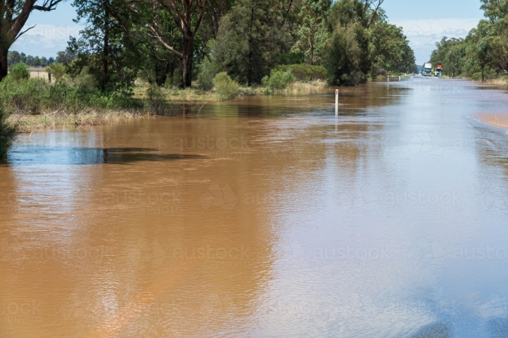 Dirty flood waters across a country road - Australian Stock Image