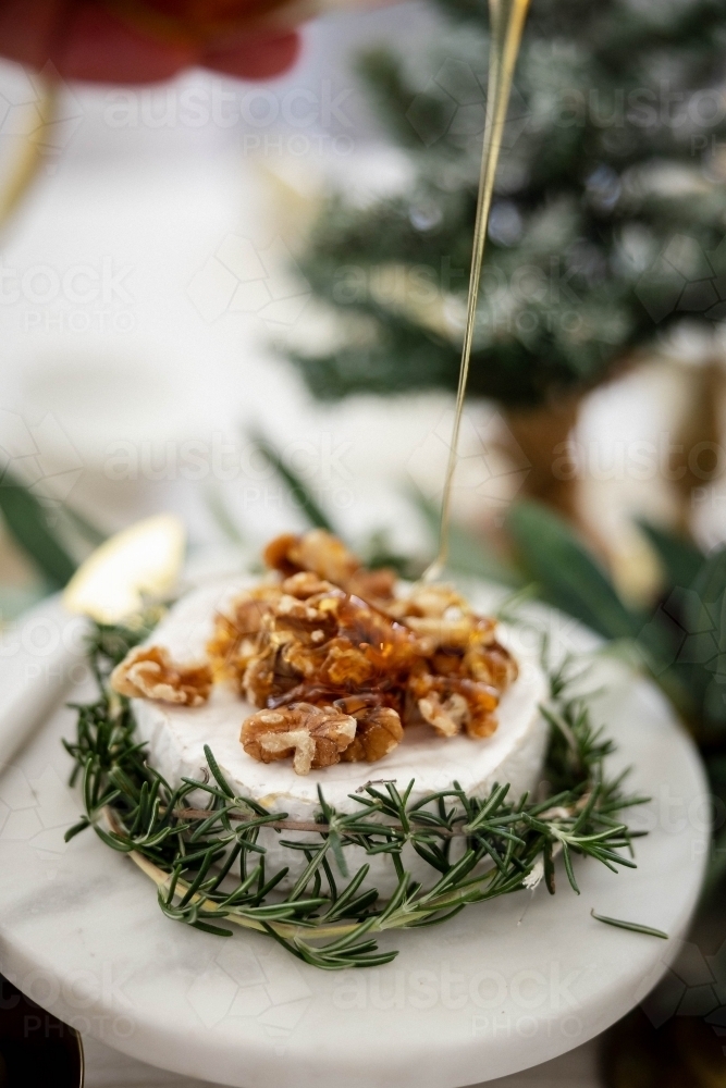 Dish of Camembert with rosemary and walnuts on decorated Christmas table - Australian Stock Image