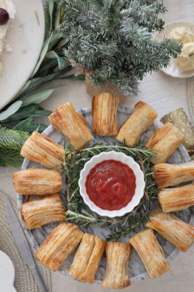 Dish of savoury pastries on Christmas-decorated table - Australian Stock Image