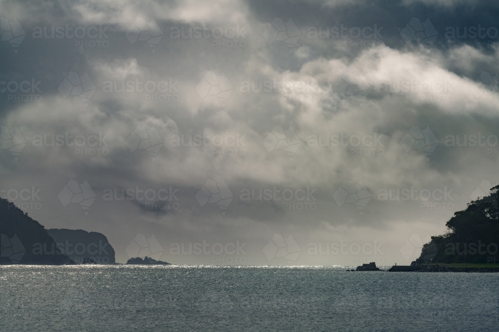 Image of Distant view of dark storm clouds between two coastal ...