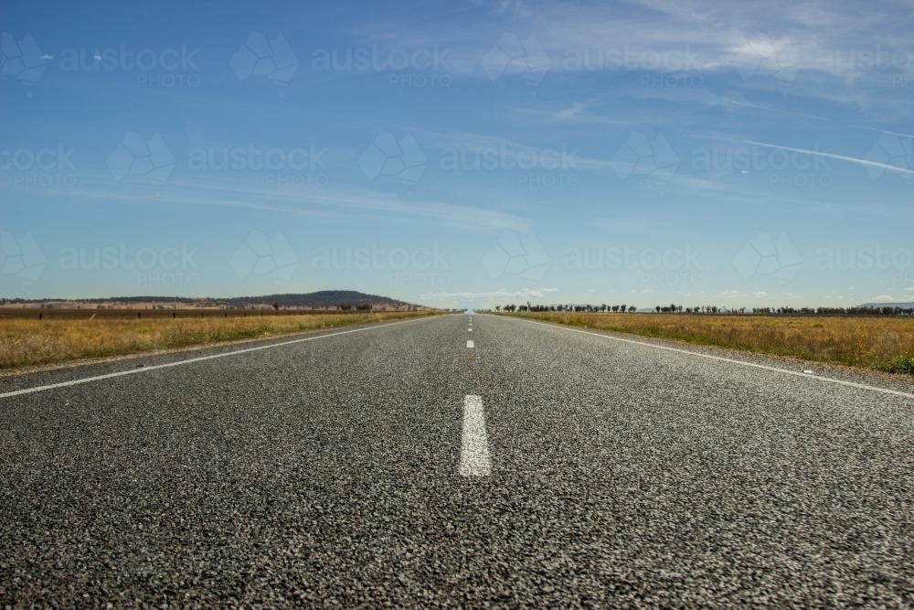 Down low view of a dead straight road - Australian Stock Image