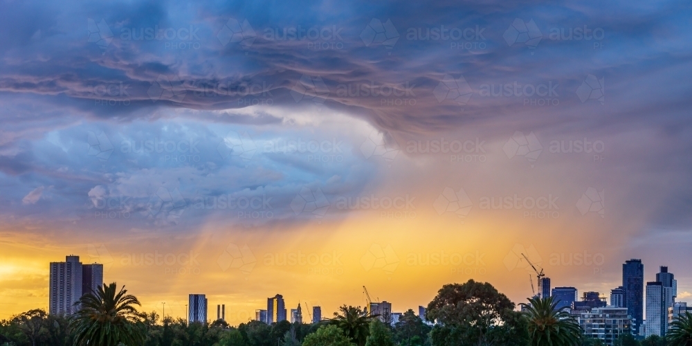 Dramatic cloud formations over a city skyline at sunset - Australian Stock Image