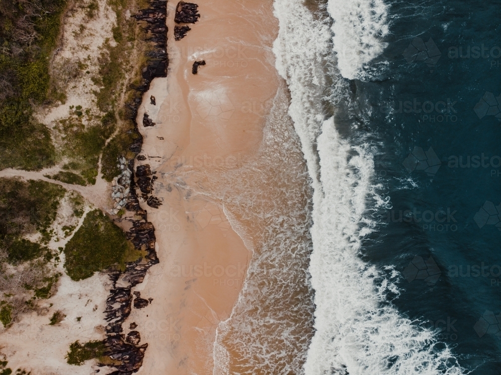 Drone shot of waves crashing on a beach from above - Australian Stock Image