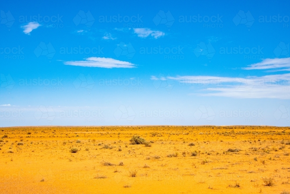 Dry, barren, orange land against the blue sky. - Australian Stock Image