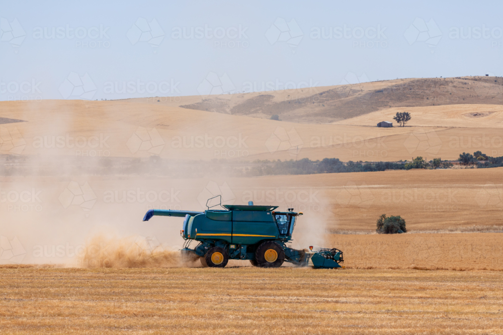 Dry-land farming machinery harvesting crop in farm paddock - Australian Stock Image