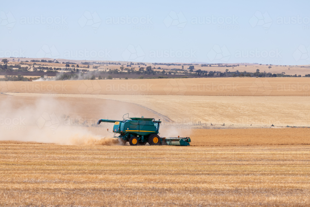 Dry-land farming machinery harvesting crop in farm paddock - Australian Stock Image