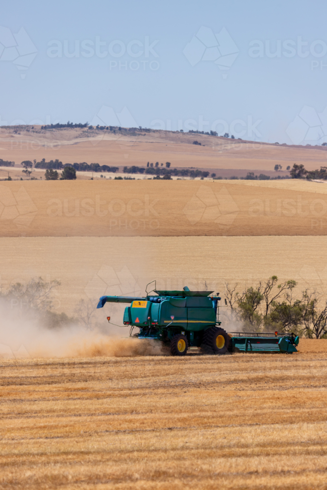 Dry-land farming machinery harvesting crop in farm paddock - Australian Stock Image