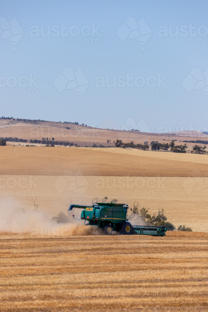 Dry-land farming machinery harvesting crop in farm paddock - Australian Stock Image