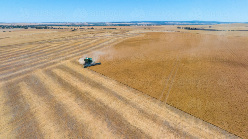 Dry-land farming machinery harvesting crop in farm paddock - Australian Stock Image